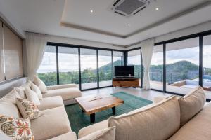 a living room with couches and a tv and windows at Titine Villa in Srithanu