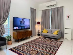 a living room with a tv and a couch at A home with private pool, KebunStorey in Tangga Batu