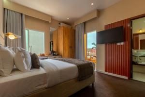 a bedroom with a large bed with a flat screen tv at Kululwa House in Luanda