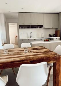a kitchen with a wooden table and white chairs at Endless Blue Anesea House in Provatas +10 photos