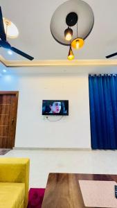 a living room with a couch and a tv on a wall at Warm Nest in Dehradun