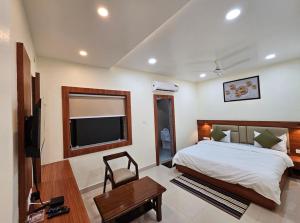 a bedroom with a bed and a flat screen tv at Hotel Sunrise in Damoh