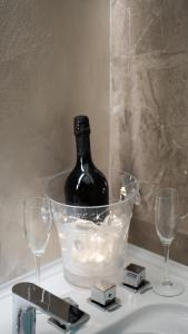 a bottle of wine in a bucket on a counter with glasses at Elysium suites & Spa in Barletta