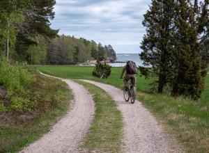 a man riding a bike down a dirt road at Marinans Guesthouse in Nävekvarn