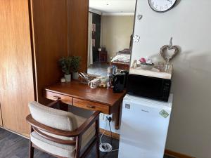 a kitchen with a desk and a microwave on a refrigerator at Cloete Self Catering Sky Room in Ermelo