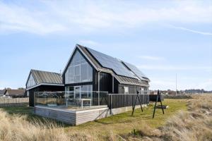 a house with a black roof in a field at 1356-Thisted-Nordsovej-106 in Thisted