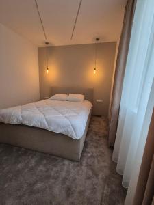 a bedroom with a bed with white sheets and lights at Апартамент Top Central in Yambol