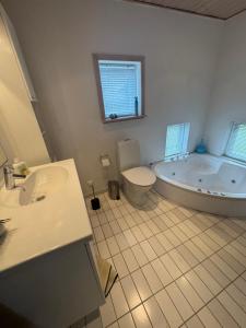 a bathroom with a tub and a toilet and a sink at Marielyst feriehus in Bøtø By