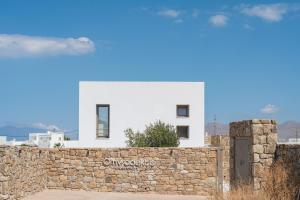 a white house behind a stone wall at Omvrodektis Village in Mykonos Airport +40 photos
