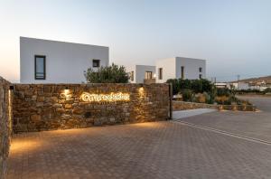 a stone retaining wall with a sign on it at Omvrodektis Village in Mykonos Airport