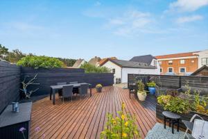 a patio with tables and chairs on a wooden deck at 1075-Hanstholm-Badsgardsvej-25 in Hanstholm