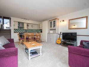 a living room with purple couches and a table and a kitchen at 2 Bed in Bridport oc-dc162 in Chideock