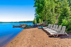 a group of white chairs sitting on the shore of a lake at A Shore Thing: Beach Access in Saint Germain