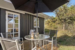 a patio with a table and chairs and an umbrella at 3392-Hvide-Sande-Fyrmarken-10 in Hvide Sande