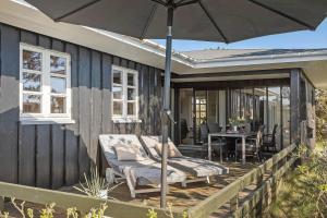 a deck with an umbrella and a table and chairs at 3392-Hvide-Sande-Fyrmarken-10 in Hvide Sande