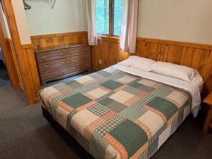 a bedroom with a bed with a quilt and a window at Pine & Paddle in Saint Germain