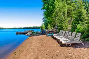 a group of white chairs sitting on the shore of a lake at Pine & Paddle in Saint Germain