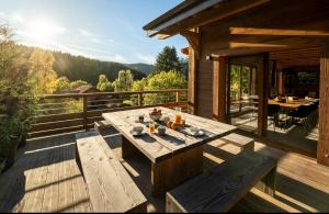 a wooden deck with a table and benches on a house at Chalet Les Cimes - Sauna - Jacuzzi in Gérardmer