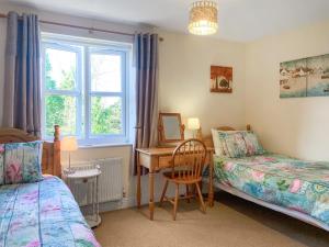 a bedroom with two beds and a desk with a mirror at Middle Cottage in Thirsk
