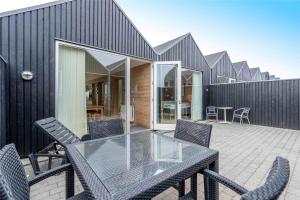 a black house with a glass table and chairs at 711-Hvide-Sande-Slusen-11 in Hvide Sande
