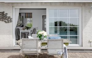 a patio with a table and chairs and a window at Ferienhaus Weitblick in Morsum