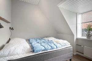 an unmade bed in a white room with a window at 890-Hvide-Sande-Bredgade-3-B-1 in Hvide Sande