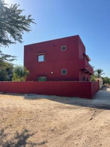 a red building with a red fence in front of it at Auberge Andel Diabou SARR in Palmarin