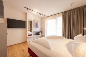 a hotel room with two beds and a television at Etra Suites & Apartments in Riva del Garda