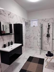 a white bathroom with a sink and a shower at Léda Vendégház in Vásárosnamény