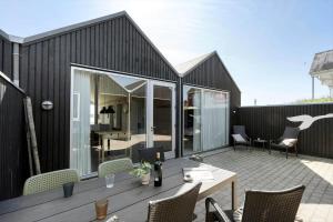 a black house with a table and chairs on a patio at 701-Hvide-Sande-Slusen-1 in Hvide Sande