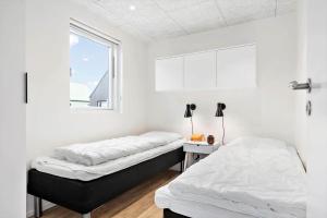 two beds in a white room with a window at 941-Hvide-Sande-Langsand-167 in Hvide Sande