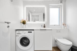 a white bathroom with a washing machine and a window at 948-Hvide-Sande-Langsand-226 in Hvide Sande +28 photos