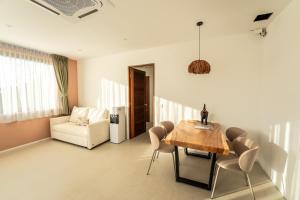 a dining room with a table and chairs and a couch at Titine Apartment in Srithanu
