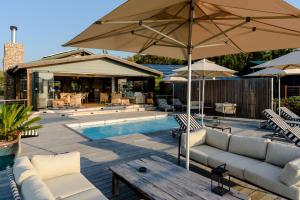 a patio with a pool with a couch and an umbrella at Elephant Hide of Knysna Guest Lodge in Knysna