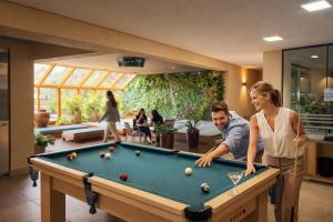 a man and a woman playing a game of pool at Hotel Thomasi Express in Maringá