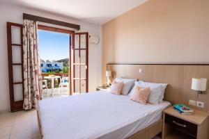 a bedroom with a large white bed and a balcony at Casa Garden in Karpathos +20 photos