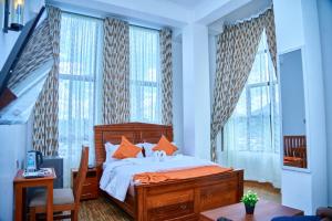 a bedroom with a bed and a desk and windows at Sumni Hotel in Nkoanrua +96 photos