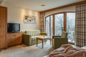 ein Wohnzimmer mit Fernseher, Sofa und Sesseln in der Unterkunft Hotel Pramstraller in Mayrhofen