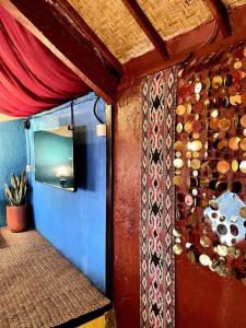 a room with a wall with a tv and a wall with a curtain at Backpackers Cabin with Mountain View in Bedugul