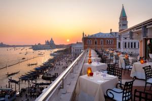 a group of tables on a balcony with a view of the water at Danieli, Venezia, A Four Seasons Hotel in Venice