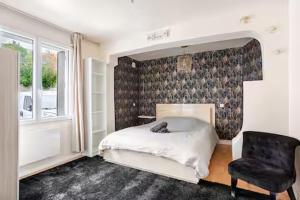 a bedroom with a bed and a chair and a window at Charme et confort in Valenton
