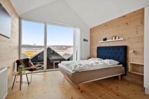 a bedroom with a blue bed and a large window at 7716-Hvide-Sande-Slusen-16 in Hvide Sande