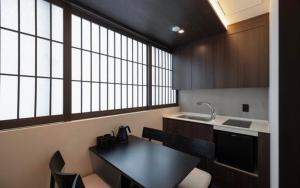 a kitchen with a black table and chairs and windows at 아늑료칸 동대구역점 in Daegu