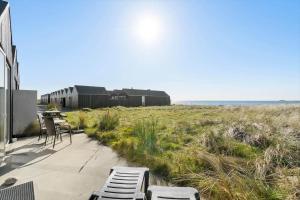 a patio with chairs and a building and a field at 745-Hvide-Sande-Slusen-45 in Hvide Sande