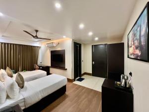 a hotel room with two beds and a flat screen tv at Hotel Mango Groves in Kotdwāra