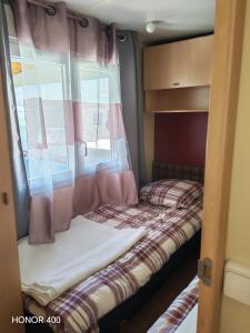 a small bedroom with a bed and a window at Mobil home au bord du lac de Foix in Foix +22 photos