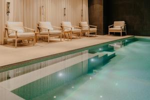 a swimming pool with chairs and a bunch ofituresitures at Maison LE GOYEN & Spa in Audierne