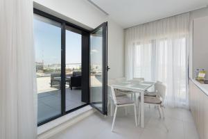 a white dining room with a table and glass doors at Athina Suites Hotel in Bucharest