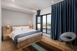 a bedroom with a bed and a chair and a window at Athina Suites Hotel in Bucharest