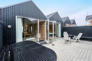 a black house with a patio with a table and chairs at 702-Hvide-Sande-Slusen-2 in Hvide Sande